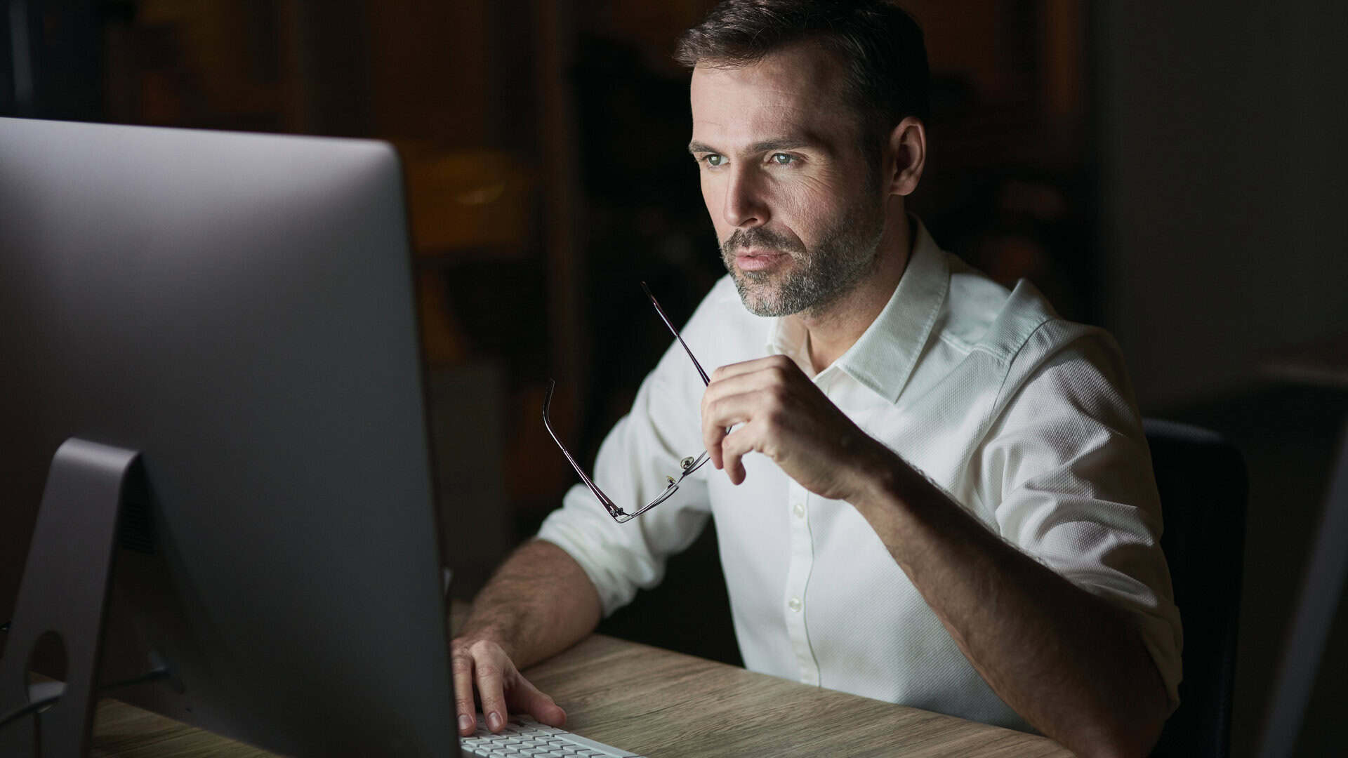 Corretor de seguros usando multicálculo no dia a dia, trabalhando à noite no computador