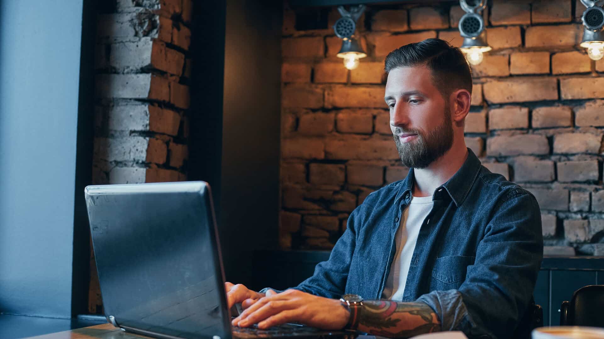 Corretor de seguros trabalhando no notebook em café, representando a rotina e os ganhos da profissão