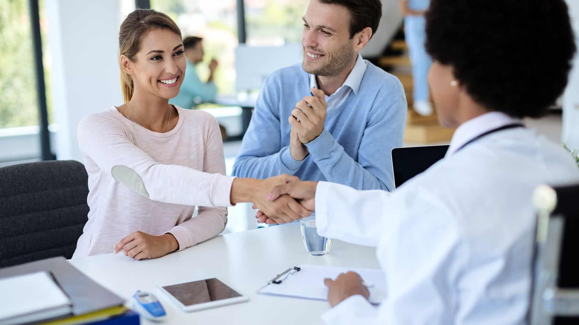 Corretor de saúde em reunião com casal de clientes — como vender plano de saúde para empresas
