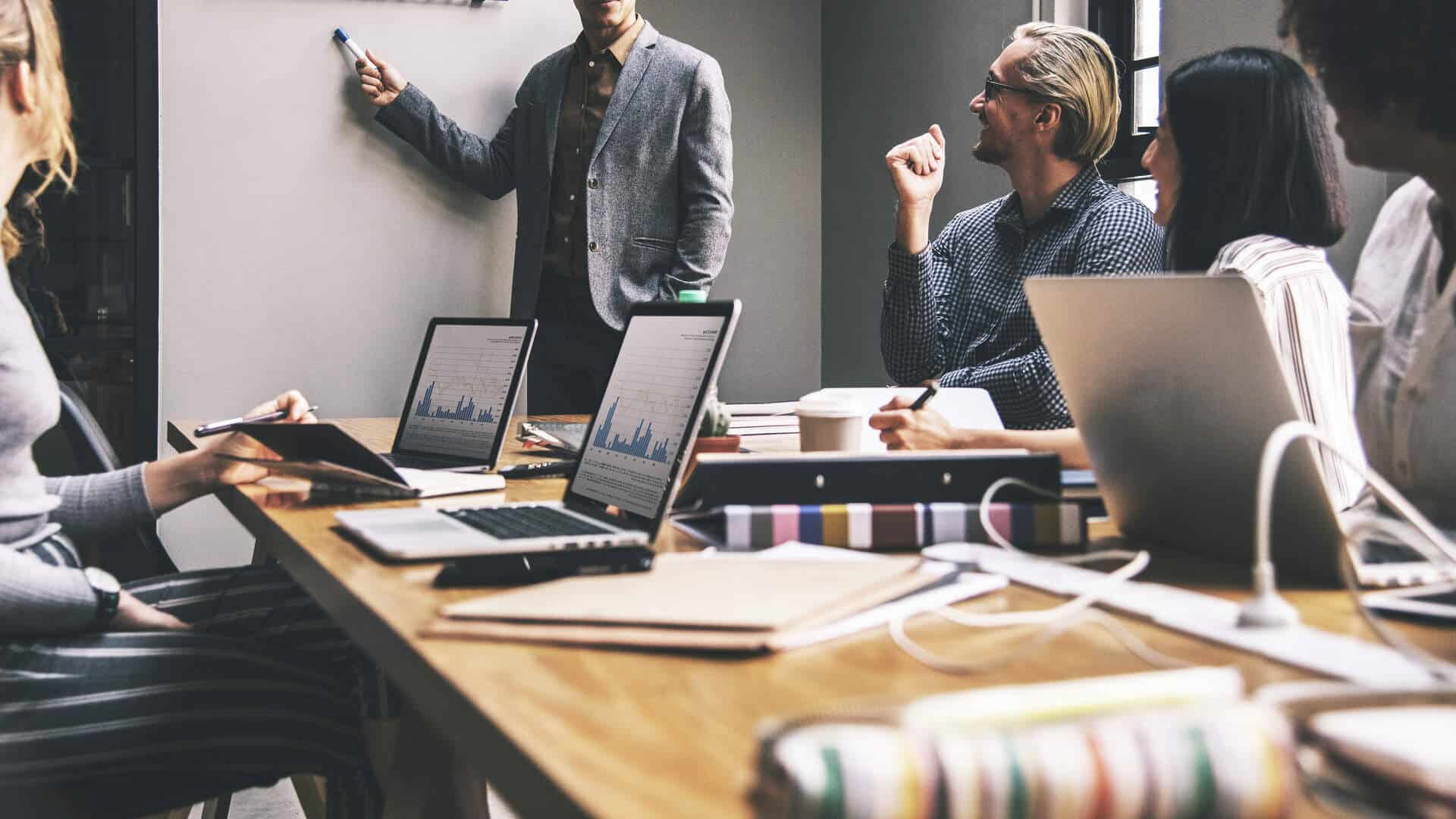 Equipe de corretores de seguros em reunião de planejamento com OKRs em quadro branco