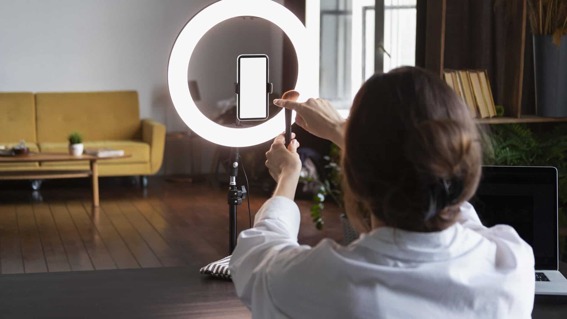 Pessoa grava vídeo no celular com ring light para Reels de corretora de seguros